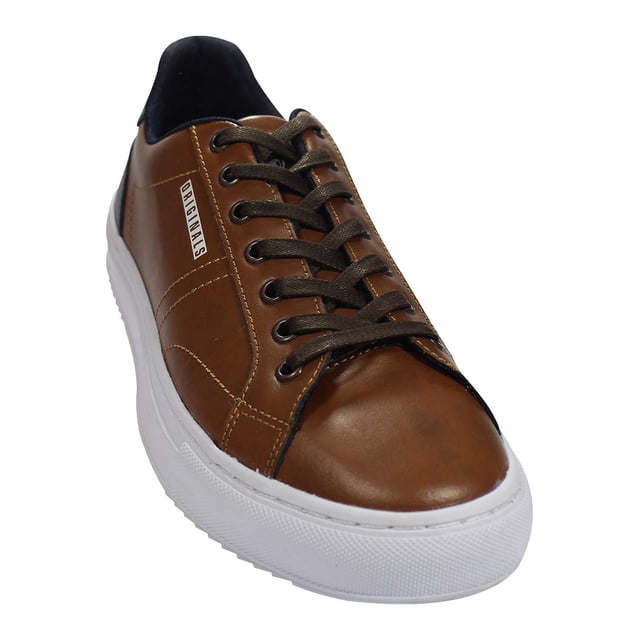 tenis casual leon hombre cafe piel 7165 Tenis casual León para hombre en piel café con suela blanca de plataforma; vista frontal 3/4 que muestra puntera redondeada, ojales metálicos, cordones café y etiqueta lateral con marca; adecuado como calzado diario y para combinaciones casuales.
