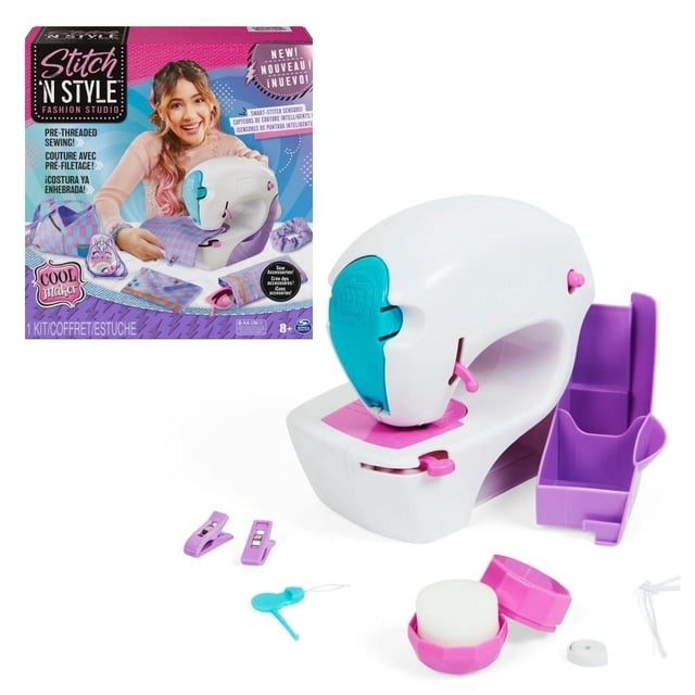 máquina de coser spin master cool maker fashion studio blanco juguete electrónico, vista 3/4 frontal; mini máquina blanca con panel turquesa y palancas rosas, base con compartimento morado para guardar materiales, incluye cartucho ya enhebrado y accesorios pequeños visibles, caja del producto al fondo; a menudo usada también para proyectos de manualidades infantiles.