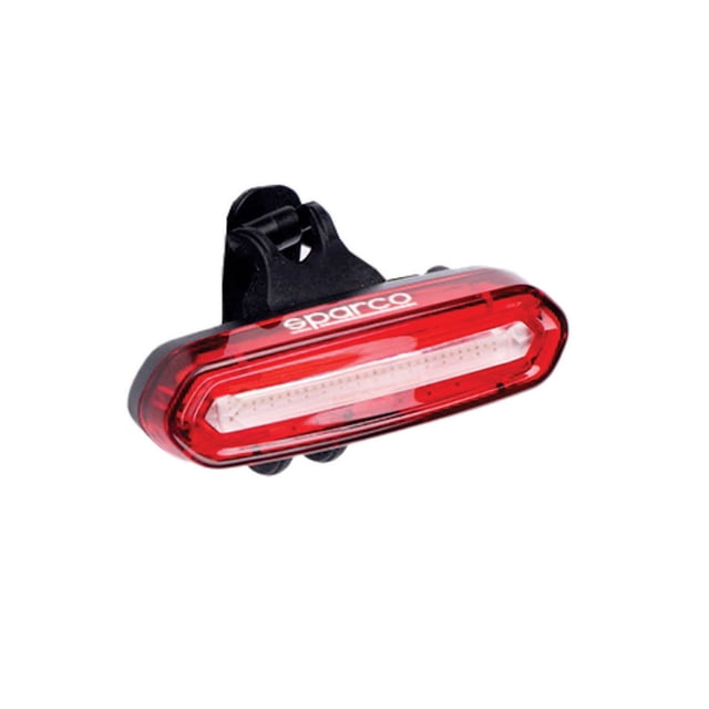sparco luz trasera led recargable 30 lúmenes impermeable para bicicleta rojo, vista frontal centrada de carcasa ovalada en PC/ABS con lente interior transparente y logo Sparco blanco, clip negro de montaje ajustable integrado, diseño compacto apto para bicicletas de montaña, carretera y urbanas, batería 400mAh recargable por USB y seis modos de iluminación; a menudo usada también como luz señaladora para mochilas en viajes cortos.