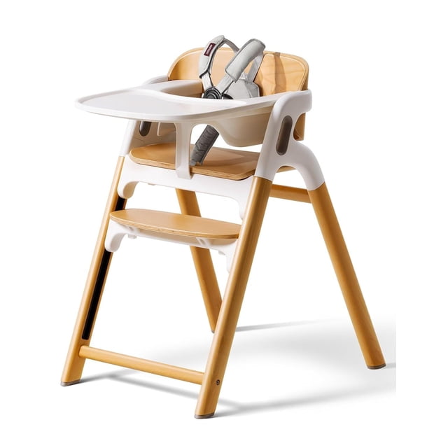 momcozy dinerpal silla de madera para bebés, trona convertible, con bandeja de grado alimenticio, ajustable — trona para bebé 5 en 1 en madera natural con bandeja extra ancha de 23.5 cm apta para lavavajillas; arnés de cinco puntos acolchado, respaldo curvado para soporte postural, asiento en 2 posiciones y reposapiés con 7 niveles; marco de haya con patas de silicona antideslizantes, vista frontal en 3/4; también suele usarse como torre de aprendizaje o taburete en etapas posteriores.