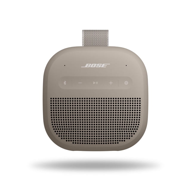 bocina bluetooth bose soundlink micro 2ª generación impermeable Sandstone, vista frontal centrada de la bocina portátil cuadrada con esquinas redondeadas, rejilla perforada en la mitad inferior, logo Bose en la parte superior, botones táctiles de reproducción y volumen visibles y correa de sujeción arriba; tamaño de bolsillo para llevar en mochila o mano, a menudo usada también para música en actividades al aire libre.