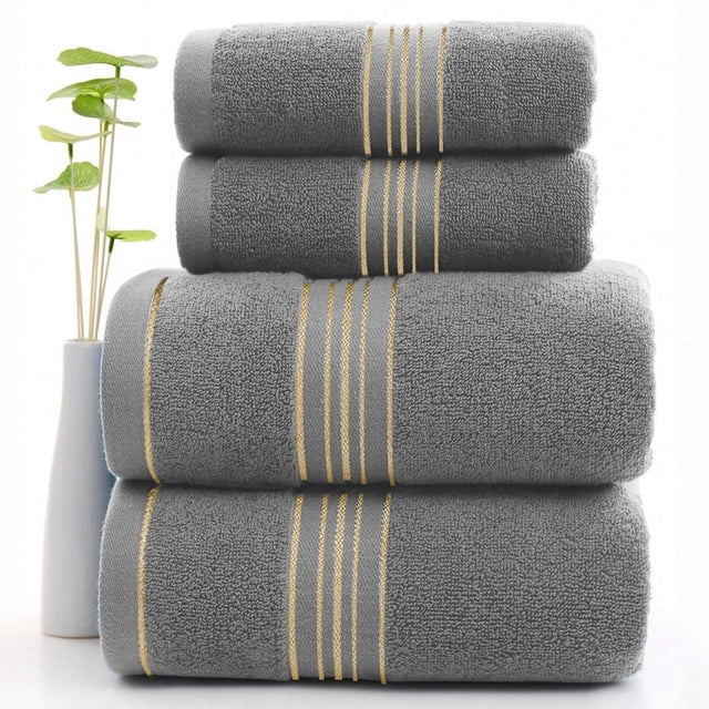 toalla grande de baño shendy vendy 100% algodón suave Gris apilada, toalla de 34x74 cm con textura de rizo de algodón y banda simple con tres líneas doradas en el borde; plegada en vista frontal sobre fondo blanco con una maceta estrecha a la izquierda, adecuada también como toalla de manos en baño de visitas.