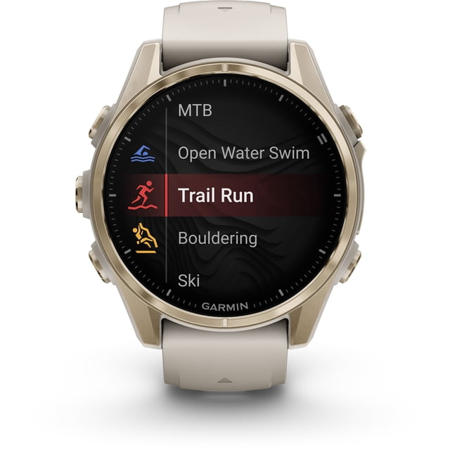 garmin, monitor deportivo, fenix 8, 43mm, amoled, sapphire soft gold Reloj multideporte 43 mm con bisel dorado y pantalla AMOLED circular mostrando modos de actividad (Trail Run resaltado), correa beige de silicón y tres botones laterales; adecuado para entrenamiento y actividades al aire libre y a menudo usado para seguimiento de rutas.