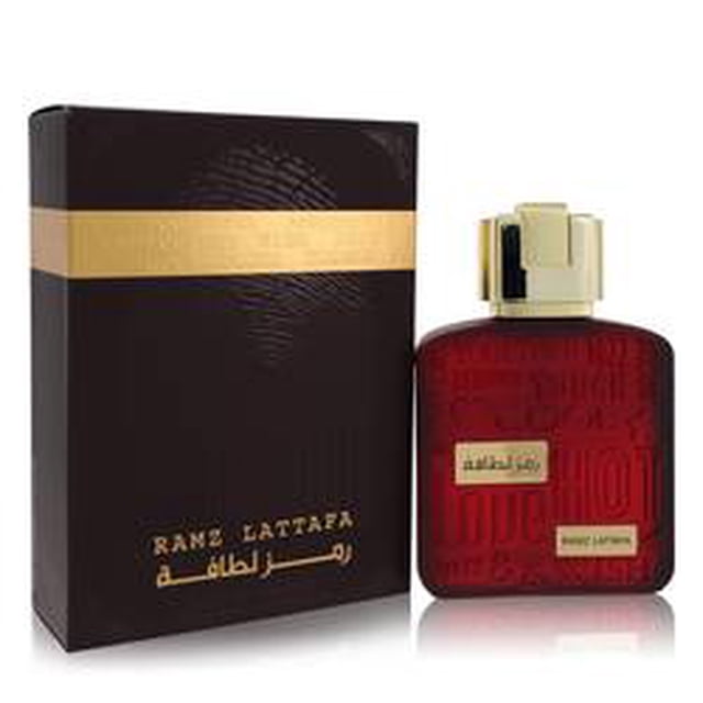 ramz lattafa gold eau de parfum spray unisex lattafa Vista frontal de botella cuadrada de vidrio rojo con tapa dorada rectangular y etiqueta pequeña dorada, junto a caja vertical marrón oscuro con banda dorada y texto en árabe y Lattafa; perfume árabe unisex, también adecuado para regalar por su presentación.