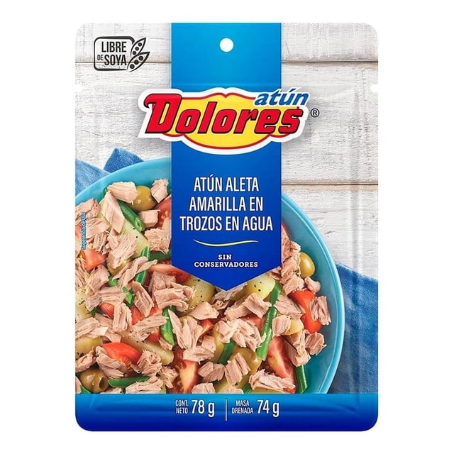 atún dolores en agua y trozos 78 g Empaque frontal centrado con logo Dolores y rótulo 'Atún aleta amarilla en trozos en agua'; se aprecia un plato con trozos de atún, verduras y aceitunas, recuadro azul 'sin conservadores' y sello 'Libre de soya', listo para consumir y adecuado para ensaladas o recetas rápidas.