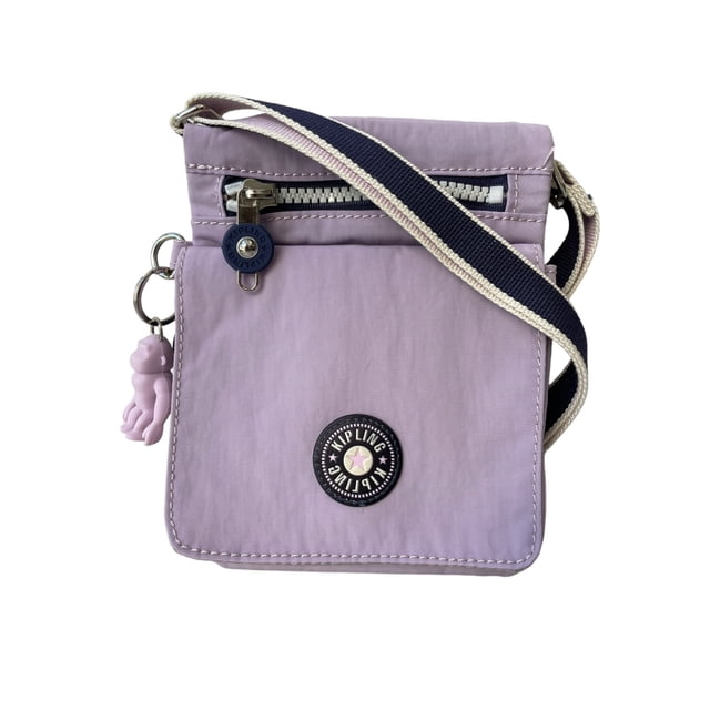 bolsa crossbody mini kipling Morado, vista frontal centrada de bandolera pequeña con solapa, cremallera externa plateada y bolsillo frontal con cierre a presión; logo circular Kipling y llavero mono colgante visibles, correa ajustable de lona a rayas. Suele usarse para llevar tarjetas y objetos de viaje gracias a sus múltiples bolsillos y ranuras para tarjetas.