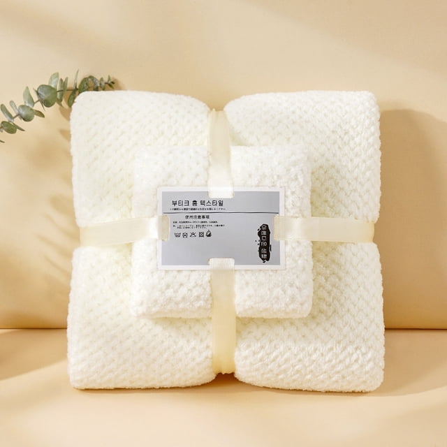 xihbxyly juego de toallas de microfibra suave, suaves y esponjosas, tacto lujoso, ideal para la decoración del baño; toalla de baño 70 x 140 cm y toalla de mano 34 x 74 cm. Vista frontal centrada de las toallas blancas apiladas y atadas con cinta color crema, textura de punto acolchado visible y etiqueta frontal de la marca; fondo neutro claro, opción habitual para ambientar baños o como set para regalo.