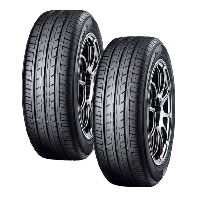 paquete de 2 llantas 185/60 r15 yokohama bluearth es32 88h dos llantas negras en vista frontal-lateral sobre rines oscuros, con bandas de rodamiento simétricas y canales longitudinales visibles, fondo blanco; según especificaciones, la gama Bluearth busca mejorar eficiencia de combustible y rendimiento en seco y húmedo; a menudo se usan también para exhibición o soporte temporal en talleres.