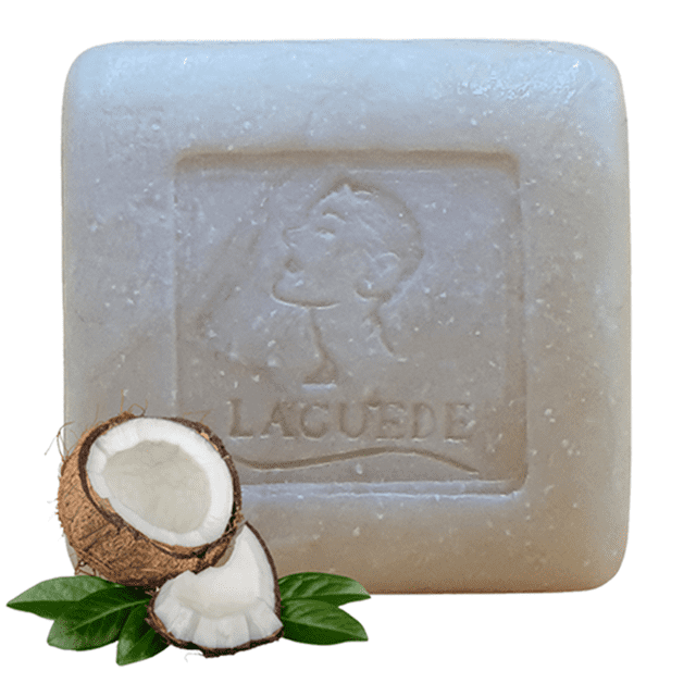 jabón natural humectante laguede 90g laguede jabón / humectante / natural Barra cuadrada transparente con relieve central de silueta facial y logo LAGUEDE, textura lisa con motas y cocos partidos con hojas; para rostro y manos, aumenta la hidratación y tiene acción anti-bacteriana y anti-fúngica; a menudo usado para higiene rápida de manos en viaje.