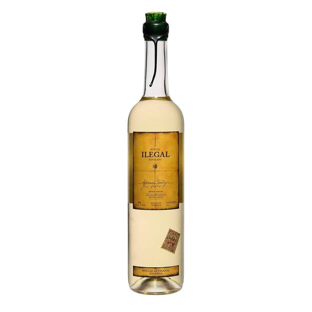 mezcal ilegal reposado 700 ml ilegal botella frontal centrada de vidrio claro, etiqueta rectangular dorada con texto 'ILEGAL' y sello pequeño en la parte baja, corcho verde con cobertura de cera en el cuello; fondo blanco, a menudo usado para degustar mezcal reposado en copas pequeñas.