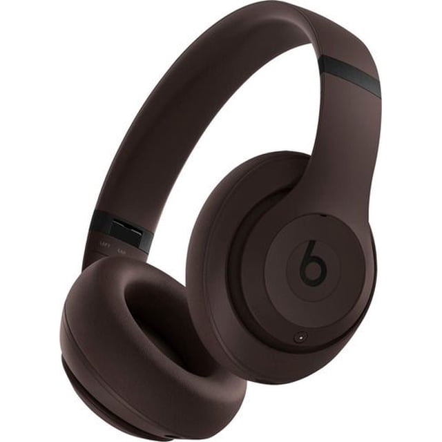 audífonos beats studio pro - café oscuro 3/4 frontal de audífonos Beats Studio Pro color café oscuro con diadema acolchada, almohadillas circumaurales, copas giratorias y logo 'b' en la orejera; controles visibles en la copa y acabado mate, aptos para audio espacial con seguimiento de cabeza y cancelación activa de ruido; también suelen usarse para monitoreo portátil en gaming y viajes.