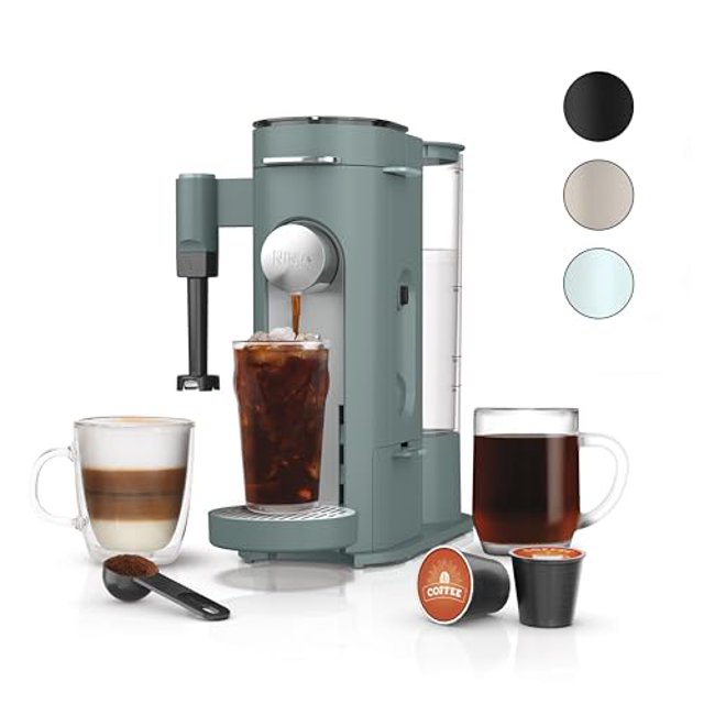 cafetera monodosis especial ninja pods & grounds, compatible con cápsulas k-cup, espumador de leche incorporado, 6 oz. taza a 24 oz. tamaños de tazas de viaje, cafetera helada, 1550 vatios, verde salv — Vista frontal de la cafetera Ninja compacta verde con depósito de agua transparente trasero y boquilla sirviendo café frío en vaso alto; se muestra el espumador incorporado y una taza estilo latte, cápsulas K-Cup y cuchara medidora con posos en primer plano; adecuada para encimeras y viajes.