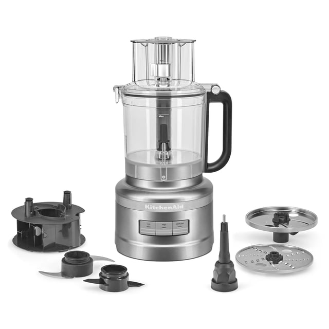 procesador de alimentos kitchenaid 13 tazas contour silver kfp1318 vista frontal con base plateada y logo KitchenAid, bol transparente Snap and Go de 13 tazas con asa negra y tapa con alimentador 3 en 1; accesorios dispuestos alrededor: organizador de almacenamiento, cuchilla multiuso, disco Exact Slice de ajuste externo, disco reversible para triturar y cuchilla de amasar. Adecuado para picar, cortar y mezclar; a menudo se usa para preparar purés para bebés.