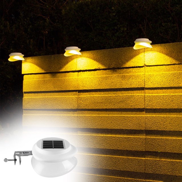 xihbxyly farola solar Iluminación exterior impermeable IP65 foco LED con sensor de movimiento, montaje ajustable; vista frontal de lámpara blanca con panel solar superior, difusor redondeado y abrazadera metálica, instalada en valla que proyecta luz cálida en jardín y patio; tamaño 13,3 x 12,7 x 6 cm.