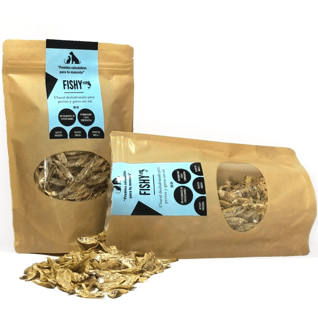 premios fishy para perros de pescado deshidratado sin sal 250 gramos spm superalimentos para mascotas premios fishy — Dos bolsas kraft con ventana mostrando charales deshidratados; etiquetas azules con logo SPM y texto 'Fishy', una bolsa de pie y otra recostada, montoncito de pescaditos delante sobre fondo blanco; snack para perro deshidratado, suele usarse también para añadir proteína a la comida del perro.
