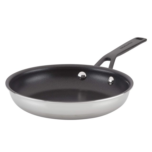 sartén kitchenaid de acero inoxidable pulido de 5 capas, 21 cm — vista frontal en ángulo; interior antiadherente negro de triple capa, base exterior pulida plateada de cinco capas, mango negro con doble remache y orificio para colgar; apta para inducción y horno hasta 500 °F. Su tamaño compacto la hace adecuada también para saltear porciones pequeñas.
