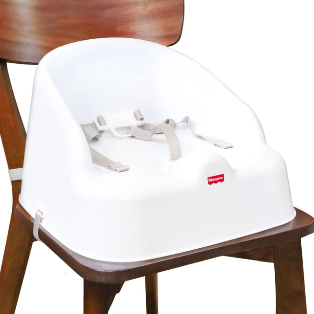 Asiento elevador Fisher-Price ligero y portátil para niños pequeños asiento elevador blanco de plástico, vista frontal centrada con respaldo curvo y contornos integrados, arnés de tres puntos gris y correas ajustables que aseguran a la mayoría de sillas de comedor, logo Fisher-Price rojo en el frente, superficies lisas fáciles de limpiar y diseño compacto y ligero; a menudo usado como asiento portátil para visitas o comidas fuera de casa.