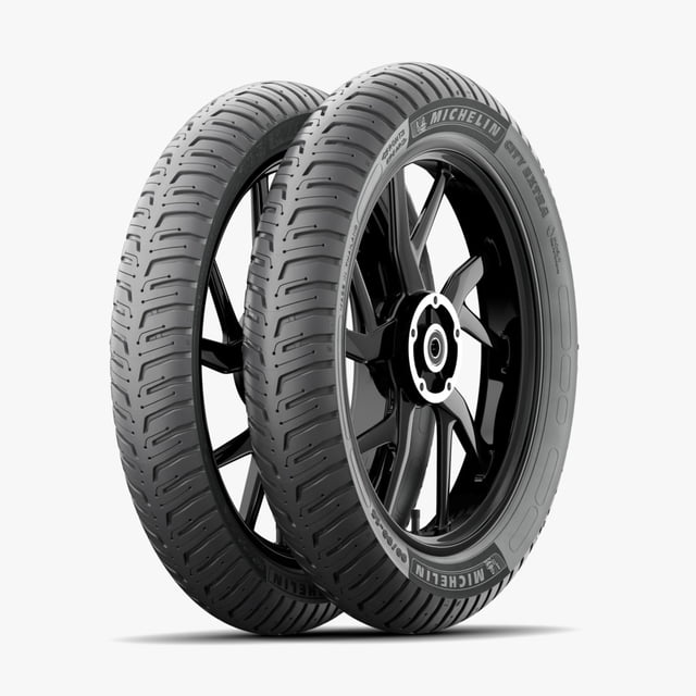 llantas de moto michelin city extra 100/90-17 55s+ 80/90-17 50s uso sin cámara, par de neumáticos tubeless negros Michelin City Extra en vista 3/4 frontal sobre fondo blanco; dibujo de la banda con ranuras longitudinales y tacos curvos, flancos con marcaje y medidas visibles, montaje sin cámara para uso urbano diario, también suelen usarse como reemplazo estándar en scooters y motos commuter.