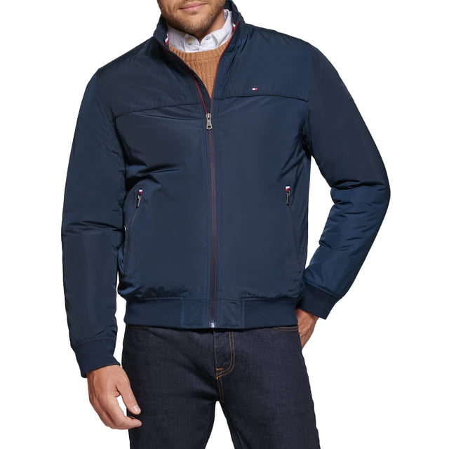 chaqueta tommy hilfiger performance faux memory navy para hombre XL chaqueta bomber azul marino de corte regular, vista frontal centrada con cremallera completa; tejido exterior resistente al agua y forro interior acolchado con relleno sintético; dos bolsillos inferiores con cremalleras visibles y bolsillo interior con cremallera; puños y cintura de punto acanalado, bandera Tommy en el pecho izquierdo, parche de goma en la manga y logo impreso en la nuca; ligera y versátil, suele usarse como capa exterior para viajes urbanos.