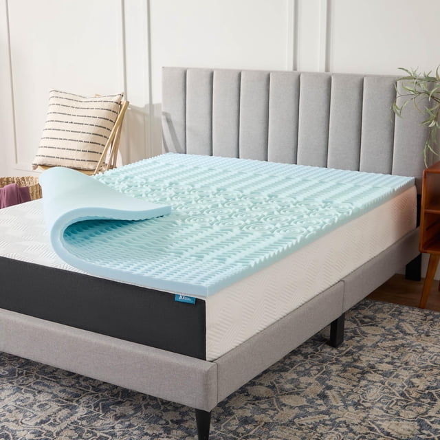 cubrecolchón lucid, espuma viscoelástica con infusión de gel, 5 zonas de confort sobre cama California King; topper azul claro de 2 pulgadas con superficie acanalada y zonas texturizadas que muestran ventilación y grosor, esquina levantada para ver el núcleo; en base tapizada gris en cuarto luminoso; también adecuado para añadir una capa extra de confort en camas de invitados.