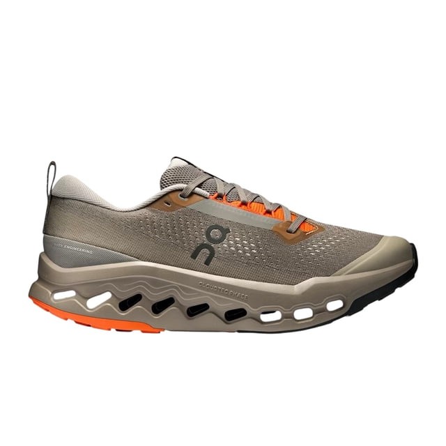 tenis on cloud cloudsurfer trail zapatilla para hombre, vista lateral derecha con malla gris topo y ojales naranjas; mediasuela beige con cavidades CloudTec Phase visibles y suela Missiongrip naranja/negra para tracción en trails cortos no técnicos; a menudo usada para salidas de senderismo ligeras y entrenamientos en caminos.