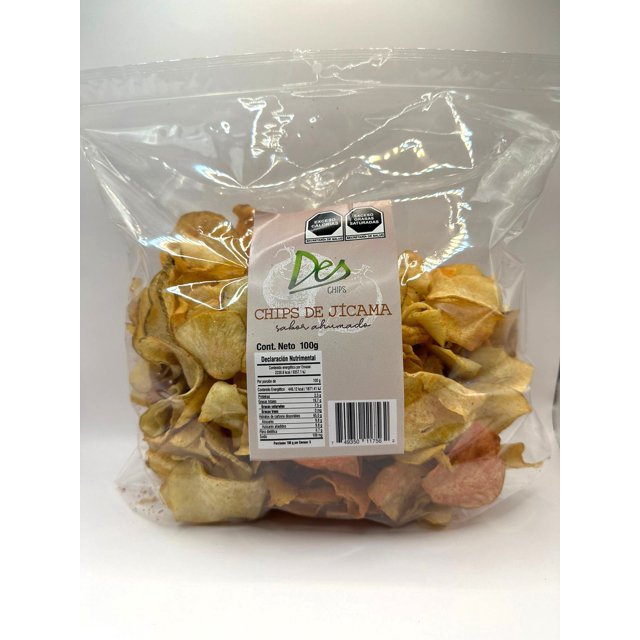 chips botana de vegetales horneados deshidratados, libres de glúten, veganas x 3 bolsas de 100 gr cada una - sabor pepino chilito. Bolsa frontal transparente con chips irregulares crema y rosa, etiqueta blanca con logo DES CHIPS y texto 'Chips de Jícama', tabla nutricional y código de barras visibles sobre fondo blanco; ideal como snack para llevar y a menudo usado como adición en ensaladas.