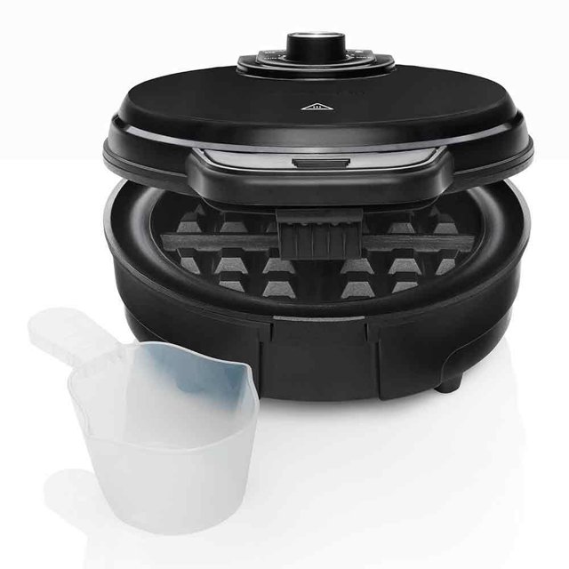 waflera belga circular chefman eléctrica antiadherente y anti-derrames negra, vista frontal 3/4 con tapa abierta; cuerpo redondo negro, mando giratorio de temperatura en la tapa, luces de encendido/listo, placas interiores antiadherentes con rejilla profunda y canal envolvente anti-derrames; incluye taza medidora translúcida en primer plano, adecuada también para preparar mezclas calientes pequeñas o calentar crepas pequeñas.
