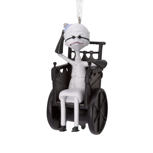 adorno navideño hallmark disney nightmare before xmas Dr. Finkelstein sentado en silla de ruedas de resina, vista frontal; figura blanca con detalles negros y grises, vendajes faciales y correas, brazo levantado mostrando la parte superior del cráneo, colgador de cinta blanca en la parte superior; aprox. 1.5 x 3.5 x 1.75 pulgadas; a menudo se usa como adición temática a árboles y decoraciones navideñas para fans.