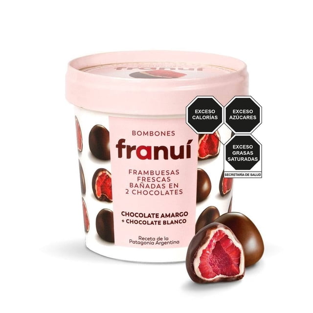 frambuesas congeladas franuí bañadas en chocolate amargo y blanco 150 g — Envase cilíndrico frontal con tapa rosa y rótulo Franuí; frambuesas individuales cubiertas con baño exterior de chocolate amargo y baño interior de chocolate blanco, una pieza cortada revela la fruta roja en el centro; etiqueta indica chocolate amargo + chocolate blanco y receta de la Patagonia; fondo blanco de estudio; también suelen usarse como topping para postres fríos.