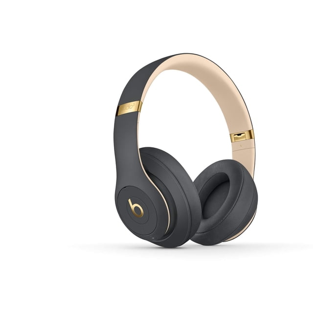 auriculares inalámbricos beats studio3 renovados - shadow grey 3/4 frontal de audífonos sobre oreja gris oscuro con detalles dorados, diadema acolchada y almohadillas giratorias ventiladas; diseño cerrado e inalámbrico que sugiere cancelación de ruido, fondo blanco. También aptos para uso prolongado y viajes cortos por su formato plegable y conexión Bluetooth.