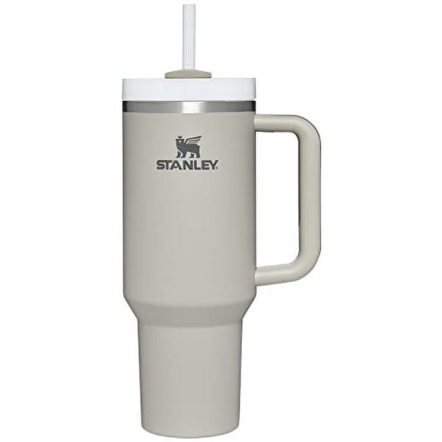 vaso stanley quencher h2.0 flowstate de acero inoxidable de 1,18 litros vaso frontal con asa; cuerpo cilíndrico beige claro de acero inoxidable reciclado con logotipo STANLEY, base estrecha para portavasos, tapa blanca FlowState con abertura para pajilla y pajilla reutilizable visible, mango ergonómico con inserto de agarre; a menudo usado también como termo de viaje para excursiones o el trabajo.