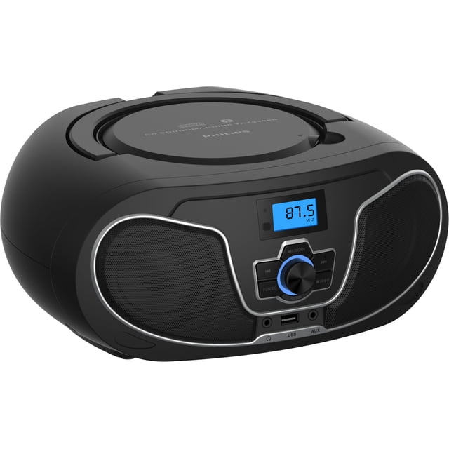 reproductor de cd philips boombox taz3300 con bluetooth y radio fm negro, vista frontal en 3/4 de un boombox compacto con bandeja de carga superior para CD, parlantes dobles con rejillas negras y marco plateado, pantalla LCD azul mostrando 87.5 MHz, perilla central y botones de control, puerto USB y entrada AUX frontales, asa integrada en la parte superior y acabado mate; también suele usarse como equipo portátil para aulas o picnics por su diseño con asa y alimentación por AC o baterías.