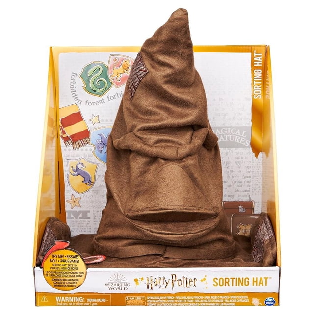 juguete interactivo spin master wizarding world sombrero seleccionador, frente centrado en caja abierta; sombrero alto color cedro con pliegues y parche cosido, boca articulada visible; base con gráficos de las casas de Hogwarts y rótulo 'Sorting Hat'; incluye movimientos faciales y sonidos para asignar la casa según personalidad; suele usarse también como pieza de colección o decoración temática.
