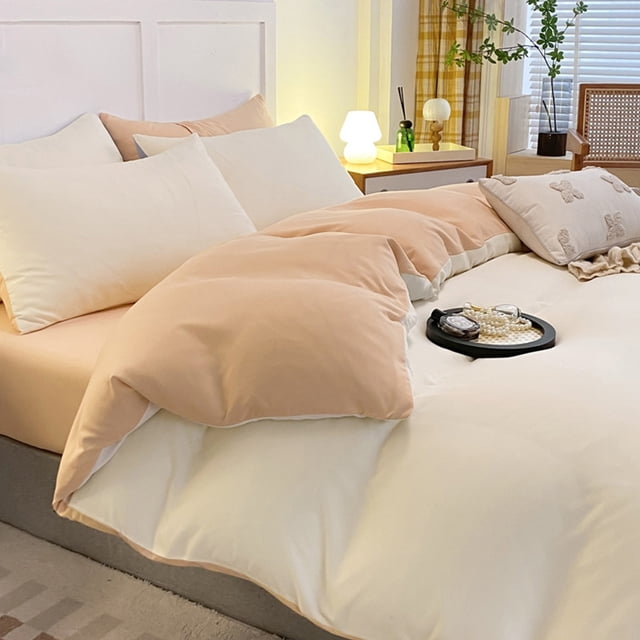 juego de cama de 4 piezas para dormitorios | poliéster suave lavado en durazno y crema; vista frontal 3/4 de funda nórdica reversible colocada sobre sábana ajustable y 2 fundas de almohada, textura lisa y caída suave, escena de dormitorio con buró y lámpara; también suele utilizarse en montajes de fotografía de interiores por su paleta neutra.