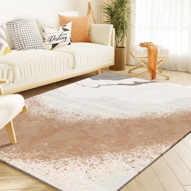 la alfombra de la sala de estar es geométricamente buena para uso doméstico. alfombra rectangular multicolor con patrón geométrico abstracto en tonos arena, rosa y gris, vista 3/4 sobre piso de madera junto a un sofá claro con cojines; textura de pelo corto y borde cosido, adecuada para sala, dormitorio y uso como tapete junto a la mesita de noche.