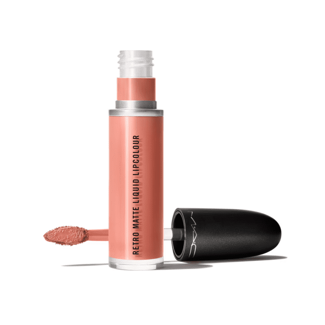 labial liquido retro matte liquid lipcolour -lady be good 5ml M.A.C, tubo cilíndrico abierto frente a cámara con aplicador tipo esponja retirado y tapa negra a un lado; tubo en tono visible con texto vertical "RETRO MATTE LIQUID LIPCOLOUR" y muestra cremosa mate en la punta del aplicador sobre fondo blanco. Fórmula de alta duración indicada; suele usarse también para retoques rápidos en viaje.