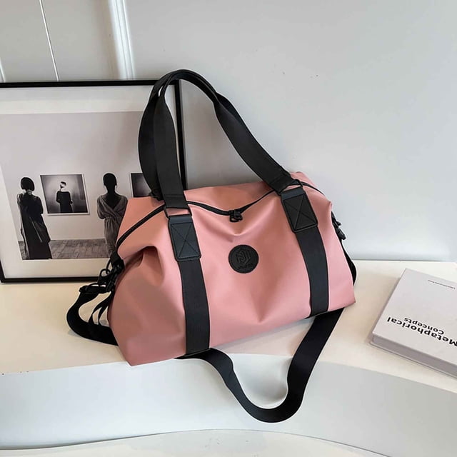 maleta cruzada plegable de gran capacidad • organizador multicompartimento • separación húmeda/seca • equipaje de mano bolsa bandolera RINYA multicolor rosa con tiras negras en vista frontal 3/4; forma tipo fin de semana con asas dobles y correa ajustable, cierre superior con cordón y placa circular de marca en el frente. Tela resistente, panel liso, múltiples bolsillos interiores y compartimento separado húmedo/seco; se pliega para guardar en el equipaje y sirve como bolsa extra para viajes de 3 a 5 días.