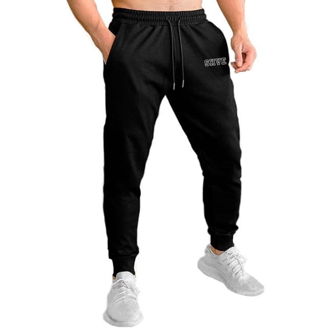 pants jogger para hombre shendy vendy deportivo slim fit elástico negro; vista frontal centrada de jogger slim con cintura elástica acanalada y cordón funcional con puntas plateadas, puños tipo jogger ajustados y bolsillos laterales visibles, modelo con tenis blancos; adecuado también para viajes cortos o descanso.