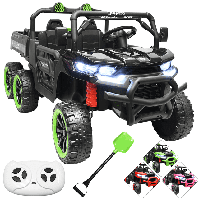 montable eléctrico para niños tractor 6x6 caja de vuelco atomática luz y sonido bluetooth 12v - negro, vista 3/4 frontal del vehículo todoterreno negro con dos asientos y cinturones, volante con claxon y panel con Bluetooth/USB, luces LED delanteras encendidas, caja de vuelco funcional, suspensión con muelle rojo y ruedas dobles traseras con aro verde; incluye control parental remoto blanco y pala de juguete; a menudo usado para juegos de imitación al aire libre.