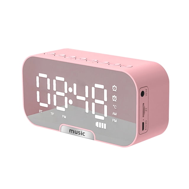 reloj despertador reloj despertador con superficie de espejo digital con altavoz bt y radio fm y pan rosa, vista 3/4 frontal con pantalla LED grande y números blancos, iconos de alarma, indicador de temperatura y nivel de batería; carcasa rectangular de plástico con bordes redondeados, botones en la parte superior, soporte oculto para teléfono y puerto DC 5V, funciones Bluetooth 5.0, radio FM y doble alarma; a menudo usado como soporte compacto para ver videos en teléfonos.