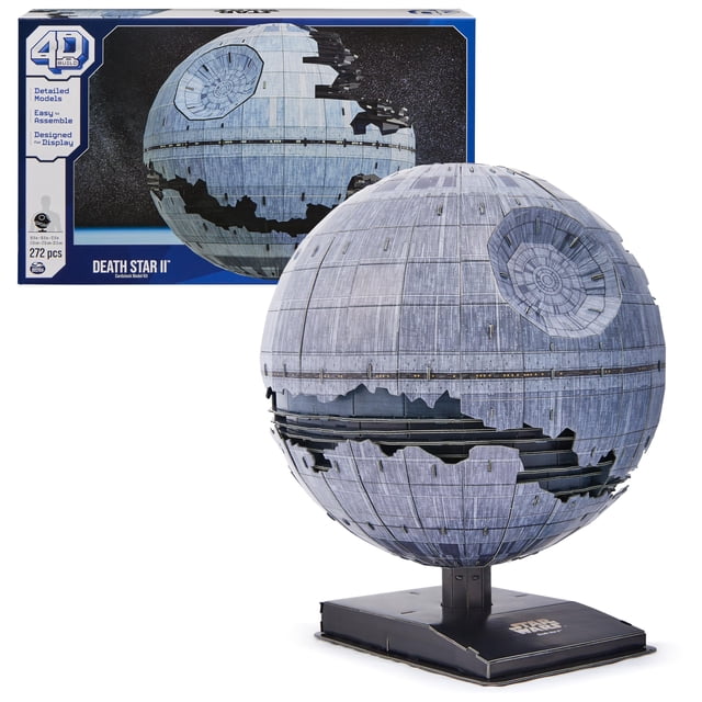 maqueta spin master games 4d build star wars death star ii Réplica esférica de cartulina de la Estrella de la Muerte II sobre soporte negro; vista 3/4 frontal con cráter del superláser, paneles texturizados y secciones destruidas visibles, caja del kit en segundo plano.