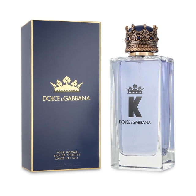 fragancia k dolce & gabbana 100ml edt spray botella y caja, vista frontal 3/4; botella rectangular de vidrio con líquido amarillo pálido y tapón con corona dorada y etiqueta con "K" y logo Dolce & Gabbana; caja azul marino con logo y bordes dorados. Familia olfativa amaderada aromática para caballero, 100 ml; también suele guardarse en estuches de viaje rígidos por su forma compacta.