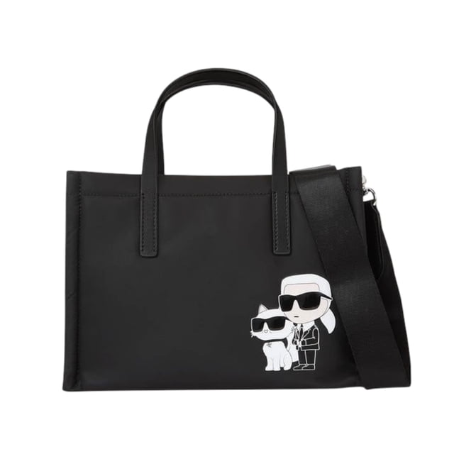 bolsa tote small karl lagerfeld nylon ikon black Bolsa tote pequeña de nylon reciclado negro, vista frontal con silueta geométrica estructurada, cierre superior con cremallera, dos asas y correa bandolera ancha desmontable; motivo IKON minimalista blanco con caricatura de Karl y su gato en la esquina inferior derecha, tejido liso y costuras visibles.