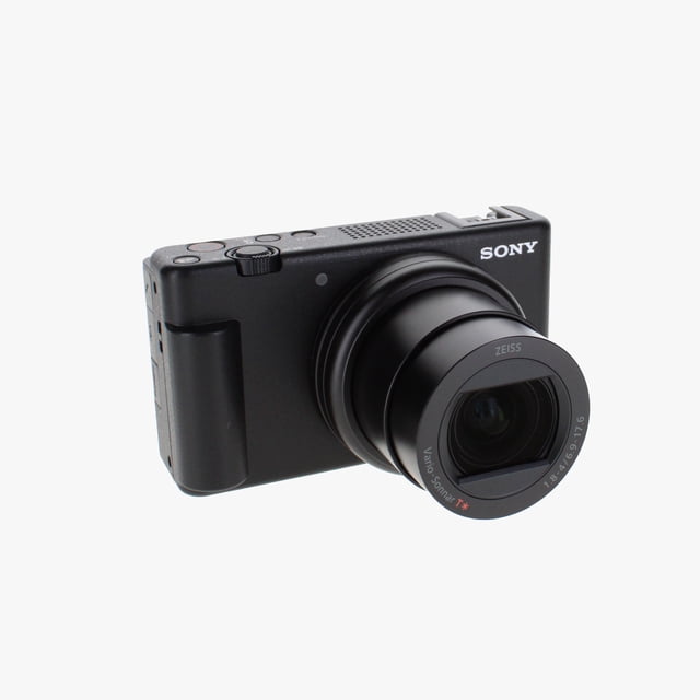 cámara vlog sony zv-1 ii para creadores de contenidos y vloggers cámara compacta negra en vista frontal 3/4 con objetivo ZEISS Vario-Sonnar T* 24-70 mm extendido, diales superiores, agarre lateral y logotipo Sony; pantalla LCD abatible para selfie, compatible con grabación 4K y seguimiento Eye AF en tiempo real, ideal para vlogs y reseñas.