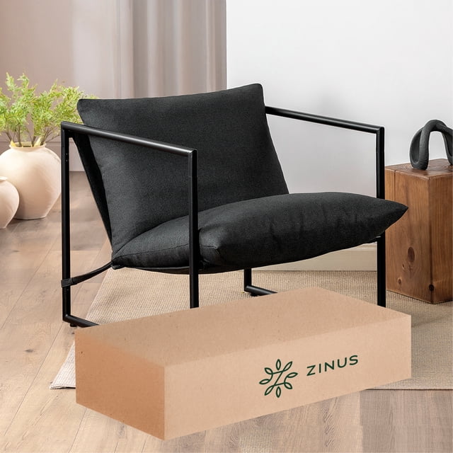 silla de metal zinus aidan con cojines de memory foam color gris oscuro silla de silueta cuadrada con estructura de acero negra, vista 3/4; cojines de tela gris oscuro con relleno de espuma triturada en asiento y respaldo; brazos de tubo metálico y patas abiertas; caja de envío Zinus en primer plano; apta también como asiento adicional en oficina en casa.