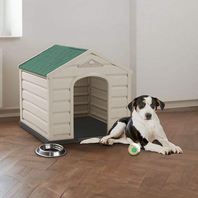casa casita hogar refugio interior exterior mascota perro ideal raza chica plástica resistente confortable rimax Refugio para perro de raza pequeña Rimax, vista frontal 3/4; estructura beige con techo verde inclinado, entrada arqueada, paredes acanaladas y base elevada oscura; dimensiones 58.5 cm alto × 68 cm ancho × 61 cm profundidad; plástico de alta resistencia, ventilación en el frontón, uso interior y exterior, fácil de limpiar y montaje sin herramientas.