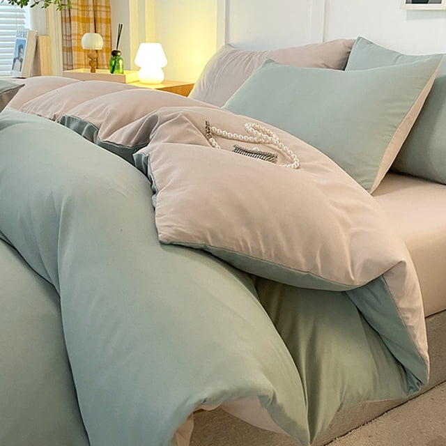 juego de cama de 4 piezas para dormitorios | poliéster suave lavado en verde agua y beige reversible, vista 3/4 frontal de funda nórdica sobre sábana ajustable con dos fundas de almohada; acabado mate y costuras visibles, fondo de dormitorio con lámpara de noche y mesa auxiliar, a menudo usado para renovar habitaciones de invitados.