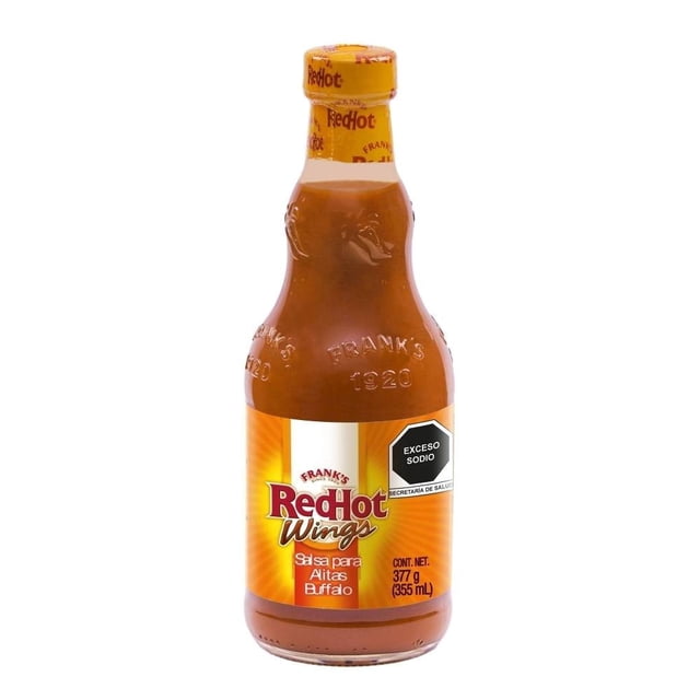 salsa picante frank's redhot wings buffalo 354 ml botella frontal con logo Frank's RedHot Wings, etiqueta naranja y tapa amarilla; salsa marrón rojiza visible en vidrio y rótulo 'Exceso sodio'. Adecuada para alitas, costillas y snacks, a menudo usada para dar picor en reuniones.