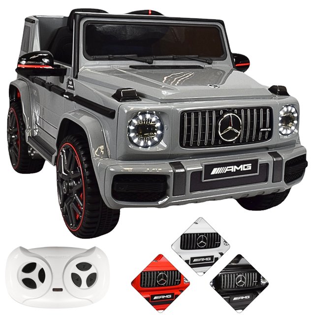 camioneta joykoo mercedes-benz montable eléctrico control remoto 12v gris vista frontal 3/4, réplica estilo G63 AMG en gris con parrilla AMG y emblema frontal, faros LED circulares encendidos, volante, asiento con respaldo y cinturón, pedal y botón de encendido, ruedas negras con ribete rojo; incluye control remoto blanco, conectividad USB/aux/SD y accesorios decorativos. Apto para niños 3–6 años (capacidad 30 kg); también suele usarse para sesiones fotográficas temáticas infantiles.