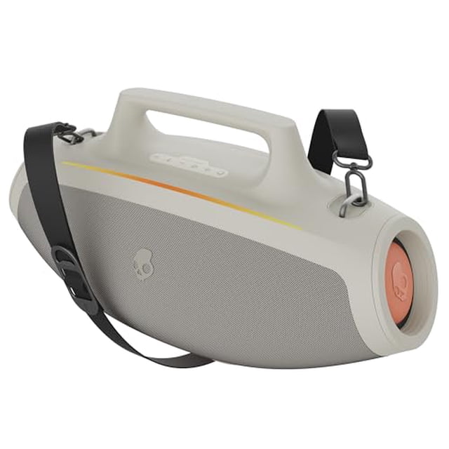 altavoz boombox bluetooth skullcandy barrel Blanco, vista 3/4 lateral con asa superior y correa ajustable; rejilla texturizada frontal, botones en la tapa y panel circular coral con logo Skullcandy en el extremo; franja LED amarilla visible. Batería 12 horas, modo espectáculo de luces, enlace múltiple y puertos USB-C y USB-A para carga; suele usarse también para llevar música a reuniones al aire libre.
